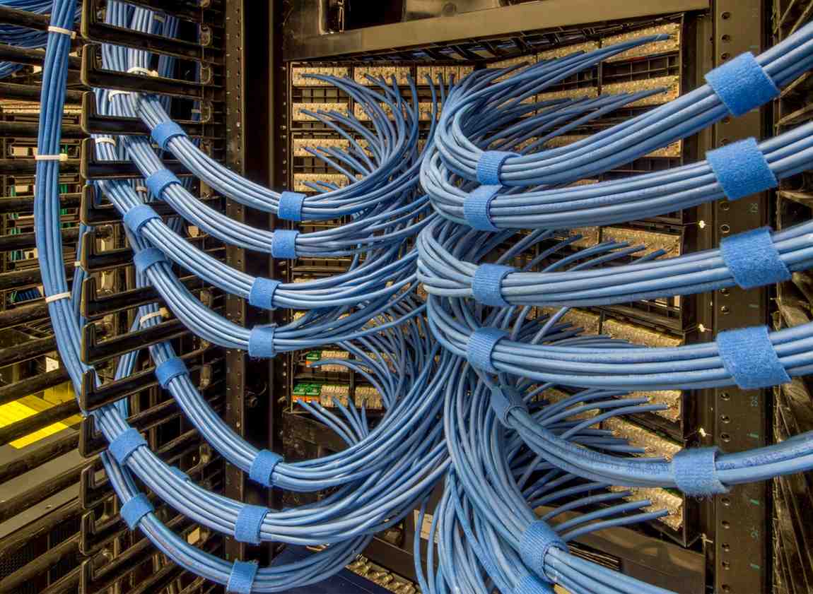Organized bundles of network cable secured with heavy-duty hook-and-loop ties in a structured cabling rack.