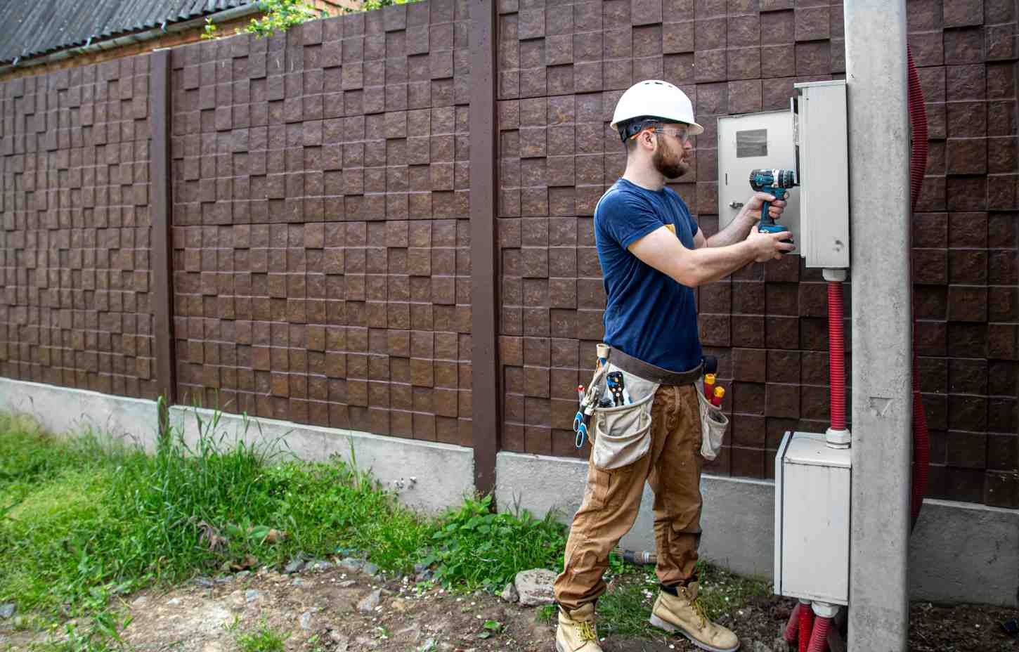 Electrician installing outdoor electrical equipment on a power distribution panel, supporting surge protection in all environments