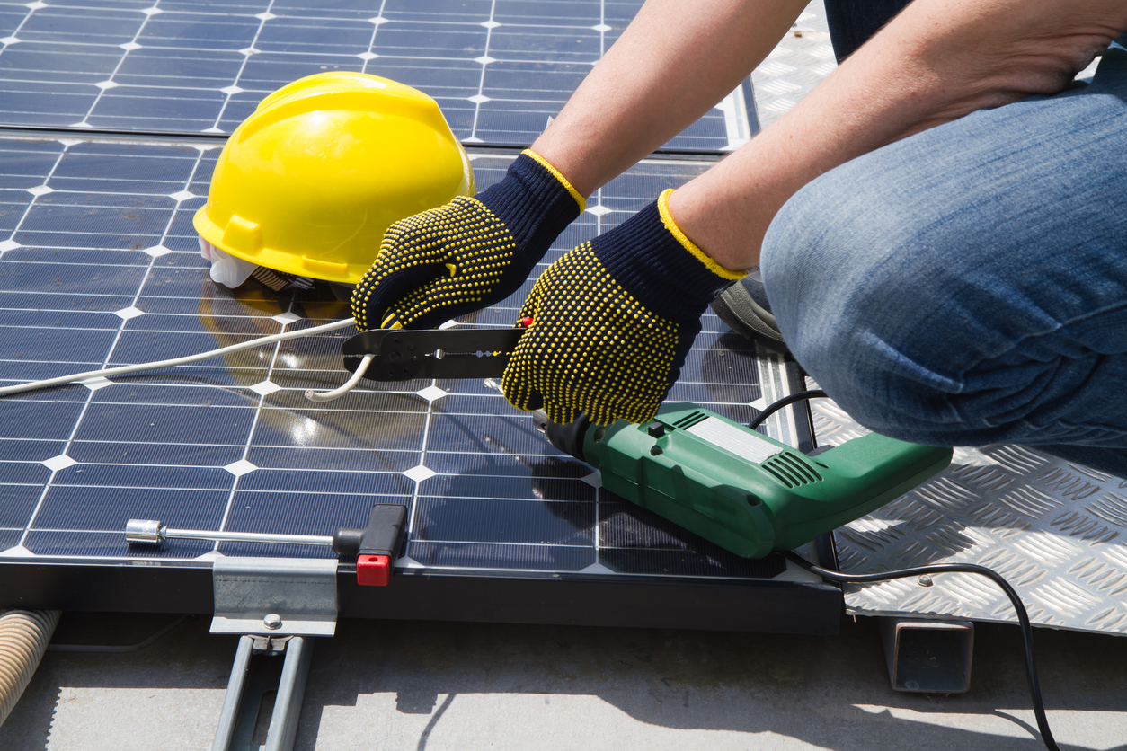 Close-up of hands wiring a solar panel using crimping tools to improve connectivity and boost energy output.