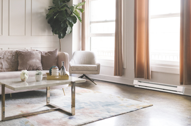 Modern living room with electric baseboard heater installed beneath windows for energy-efficient home heating.